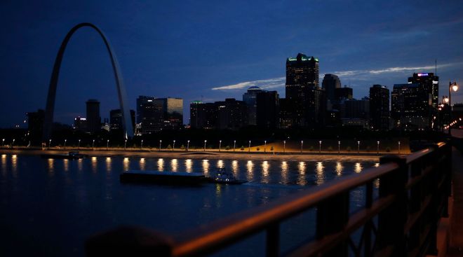 A river barge passes the St. Louis Gateway Arch at sunset along the Mississippi River in St. Louis, Mo.