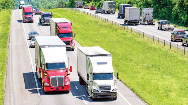 Tractor-trailers drive along a highway Tractor-trailers drive along a highway
